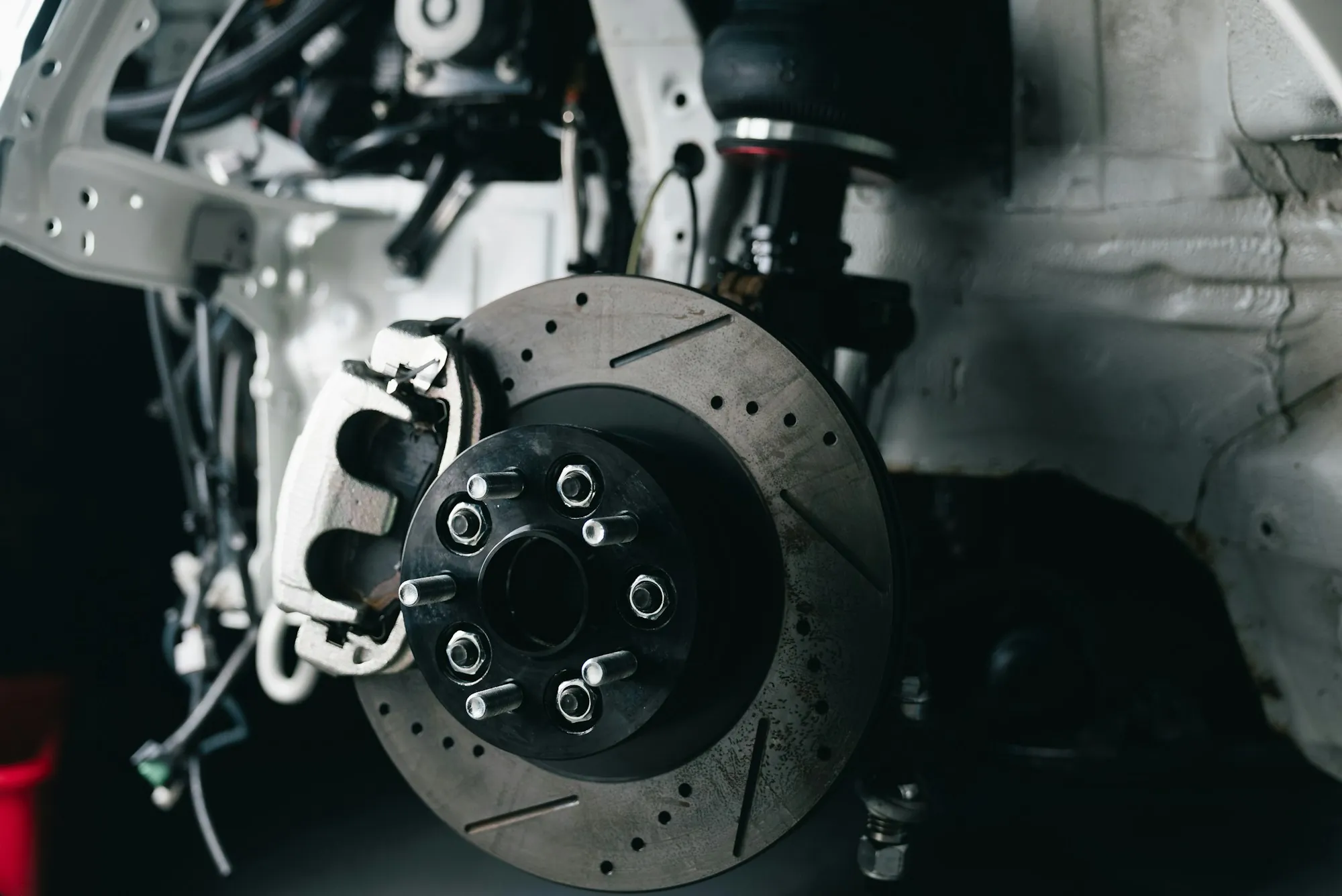 Brake caliper and slotted rotor on a vehicle in the shop