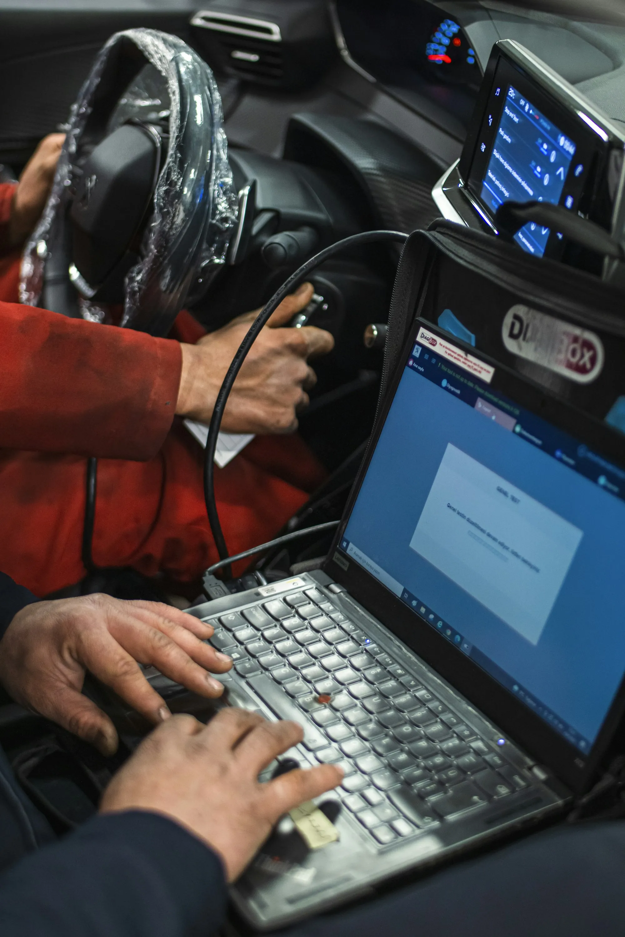 Technician with a laptop connected to a car's diagnostic port