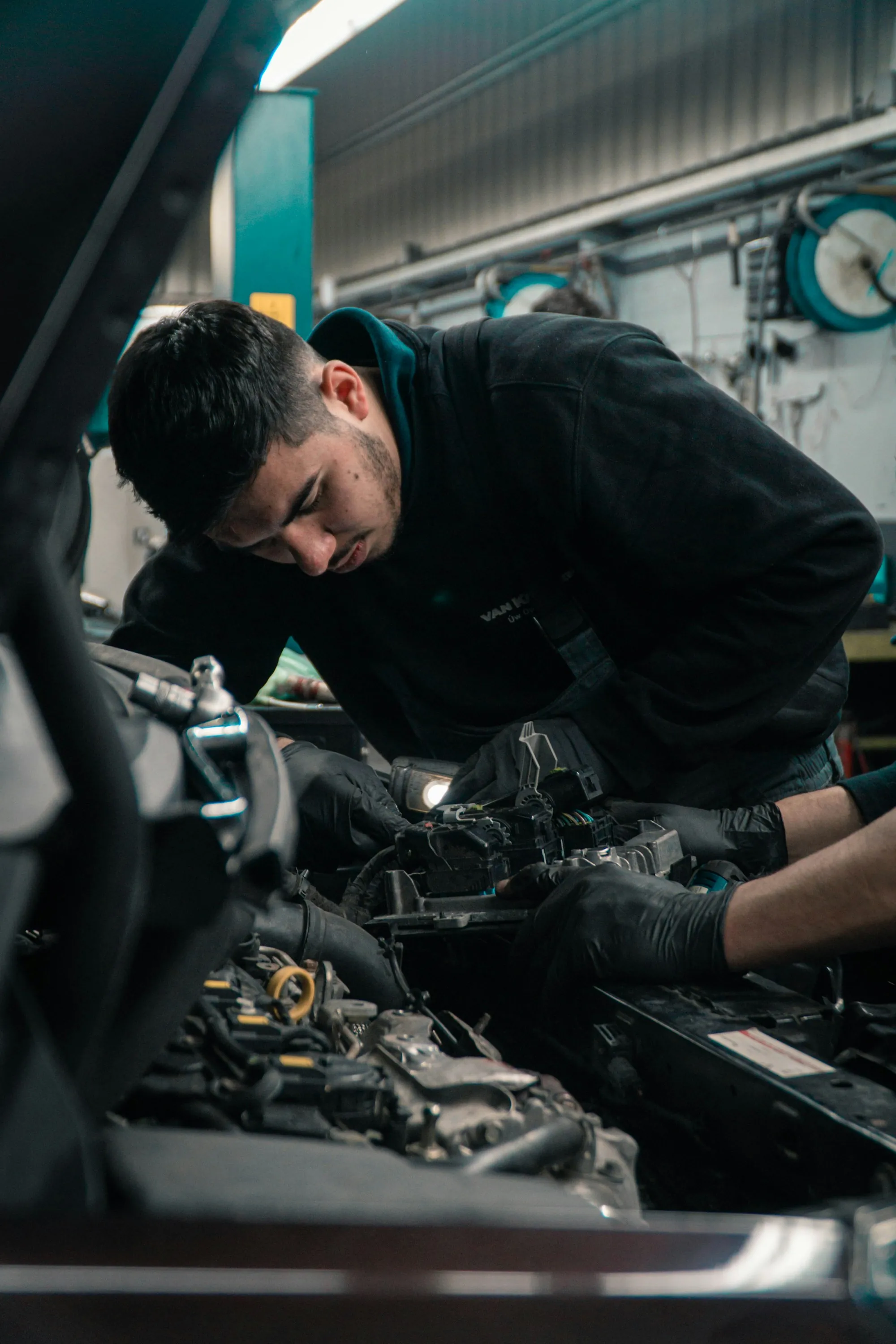 Mechanic in a tool-lined bay leaning over an engine